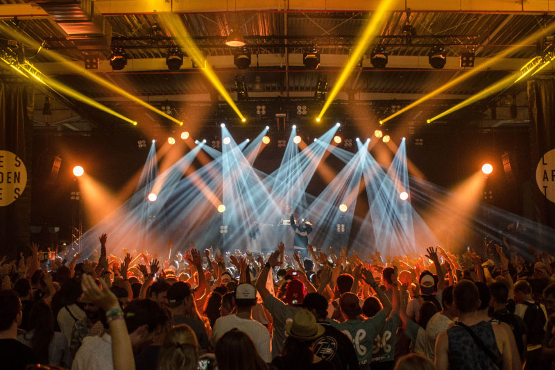 Ein großer, modernen Hangars mit einer beeindruckenden Sammlung von Fahrzeugen. Verschiedene Sportwagen in leuchtenden Farben, wie Rot, Blau und Weiß, sind auf dem Hallenboden ausgestellt. Oben links gibt es eine Galerieebene mit weiteren Exponaten. Die Dachkonstruktion ist aus Stahl und verleiht dem Raum einen industriellen Charme. Licht geht von mehreren Leuchten ab und sorgt für eine helle, einladende Atmosphäre.A large, modern hangar with an impressive collection of vehicles. Various sports cars in bright colors, such as red, blue and white, are displayed on the hangar floor. Above left there is a gallery level with further exhibits. The roof construction is made of steel and gives the room an industrial charm. Light emanates from several luminaires and creates a bright, inviting atmosphere.